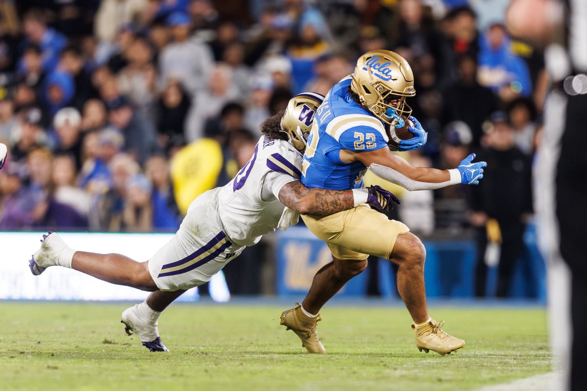 UCLA Bruins running back Anthony Frias II (22) runs the ball while getting tackled during the game against Washington Huskies at Rose Bowl Stadium on November 22, 2025 in Pasadena, California. UCLA Bruins running back Anthony Frias II (22) runs the ball while getting tackled during the game against Washington Huskies at Rose Bowl Stadium on November 22, 2025 in Pasadena, California.