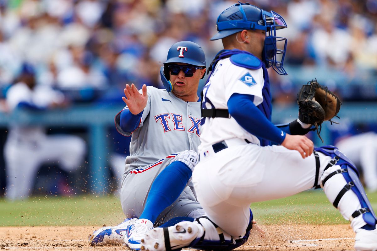 Joc Pederson #3 of the Texas Rangers slides safe into home plate against Dalton Rushing #68 of the Los Angeles Dodgers during the game at Dodger Stadium on April 12, 2026 in Los Angeles, California. Joc Pederson #3 of the Texas Rangers slides safe into home plate against Dalton Rushing #68 of the Los Angeles Dodgers during the game at Dodger Stadium on April 12, 2026 in Los Angeles, California.