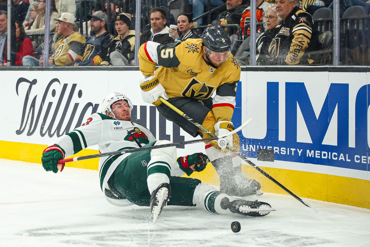 Vegas Golden Knights D Jeremy Lauzon (5) plays the puck over a falling Minnesota Wild skater during an NHL game on Monday December 29, 2025, in Las Vegas, Nevada. Vegas Golden Knights D Jeremy Lauzon (5) plays the puck over a falling Minnesota Wild skater during an NHL game on Monday December 29, 2025, in Las Vegas, Nevada.
