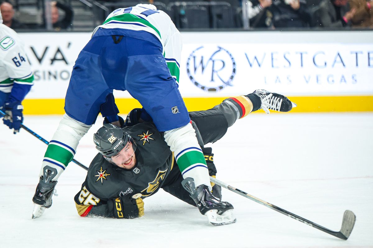 Vegas Golden Knights F Alexander Holtz (26) reaches for the puck between the legs of Vancouver Canucks D Tyler Myers (57) on Wednesday February 4, 2026, in Las Vegas, Nevada. Vegas Golden Knights F Alexander Holtz (26) reaches for the puck between the legs of Vancouver Canucks D Tyler Myers (57) on Wednesday February 4, 2026, in Las Vegas, Nevada.