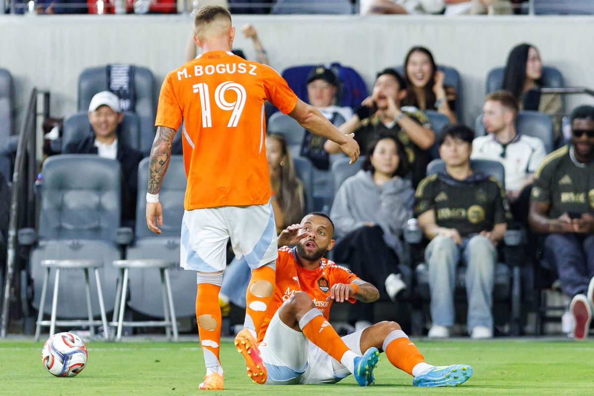 Guilherme Augusto #20 of Houston Dynamo FC gets helped up by Mateusz Bogusz #19 during an MLS match against LAFC on May 10, 2026 at BMO Stadium in Los Angeles, California. Guilherme Augusto #20 of Houston Dynamo FC gets helped up by Mateusz Bogusz #19 during an MLS match against LAFC on May 10, 2026 at BMO Stadium in Los Angeles, California.